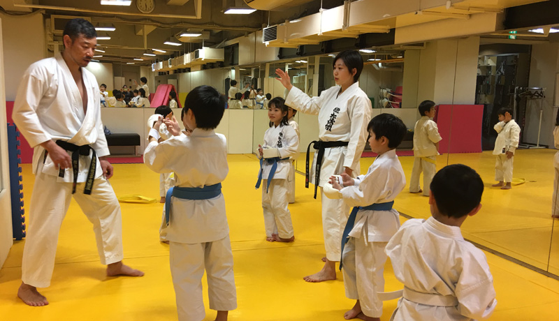 黒帯の先生と空手着を着た子供たち